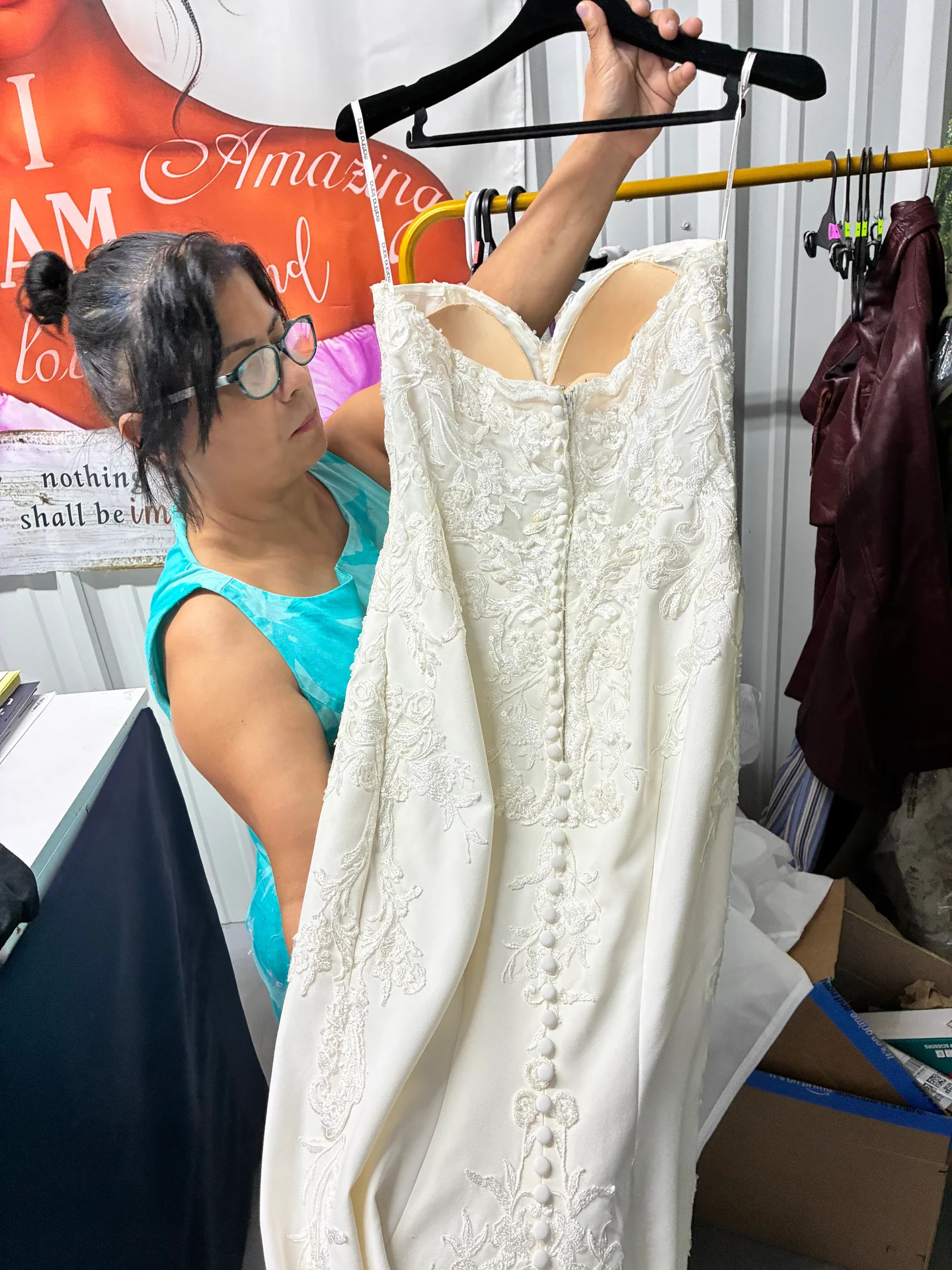 Esperanza inspecting the button back of a lace wedding gown