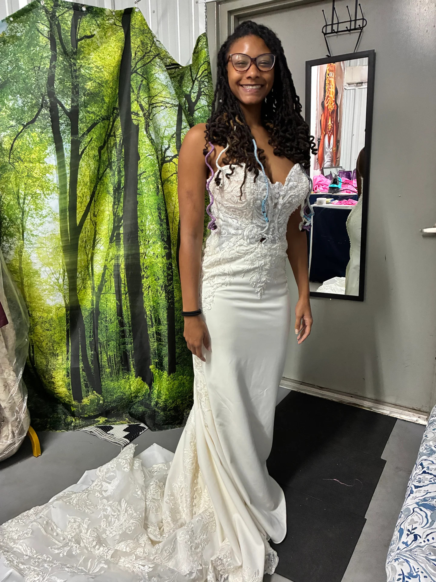 Smiling bride in a fitted lace mermaid gown during her fitting